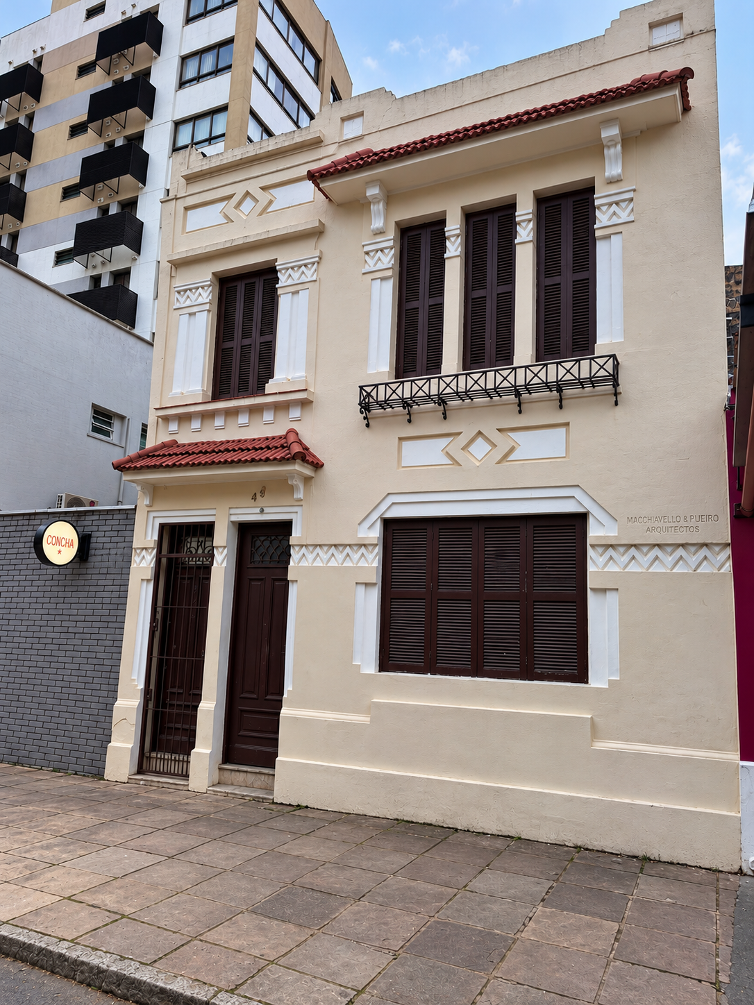 Fachada da casa onde a Argus atende, em Porto Alegre: sobrado de dois andares com frisos em zigue-zague, relevos em losango e janelas altas com venezianas de madeira.