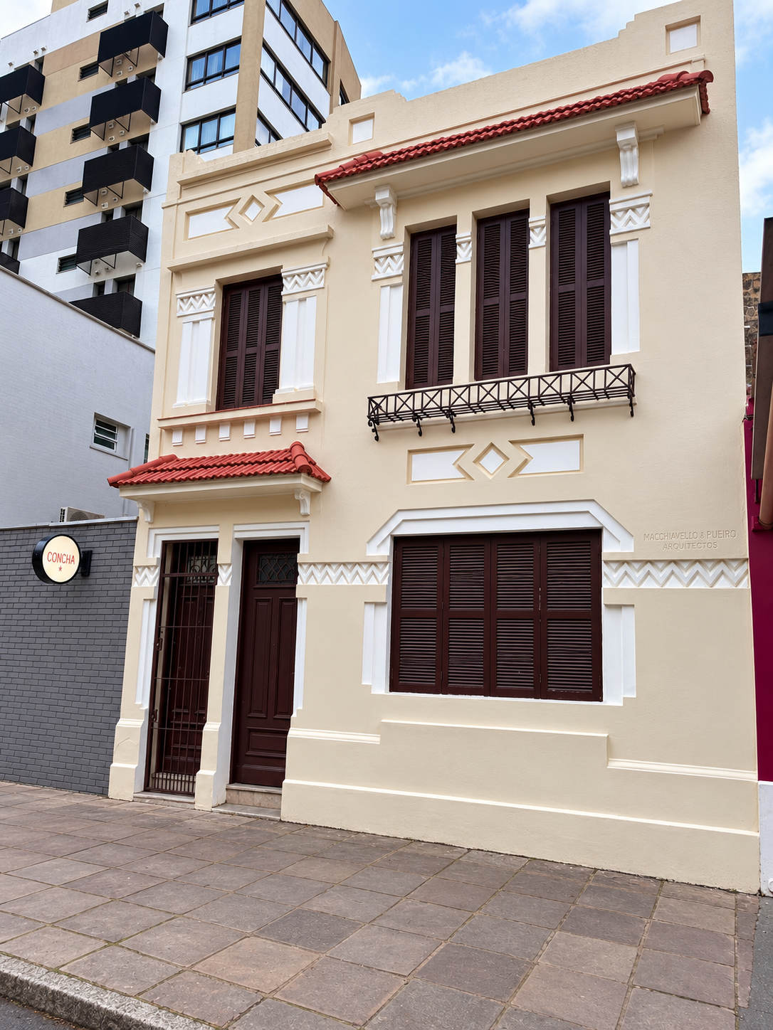 Fachada da casa onde a Argus atende, em Porto Alegre: sobrado de dois andares com frisos em zigue-zague, relevos em losango e janelas altas com venezianas de madeira.
