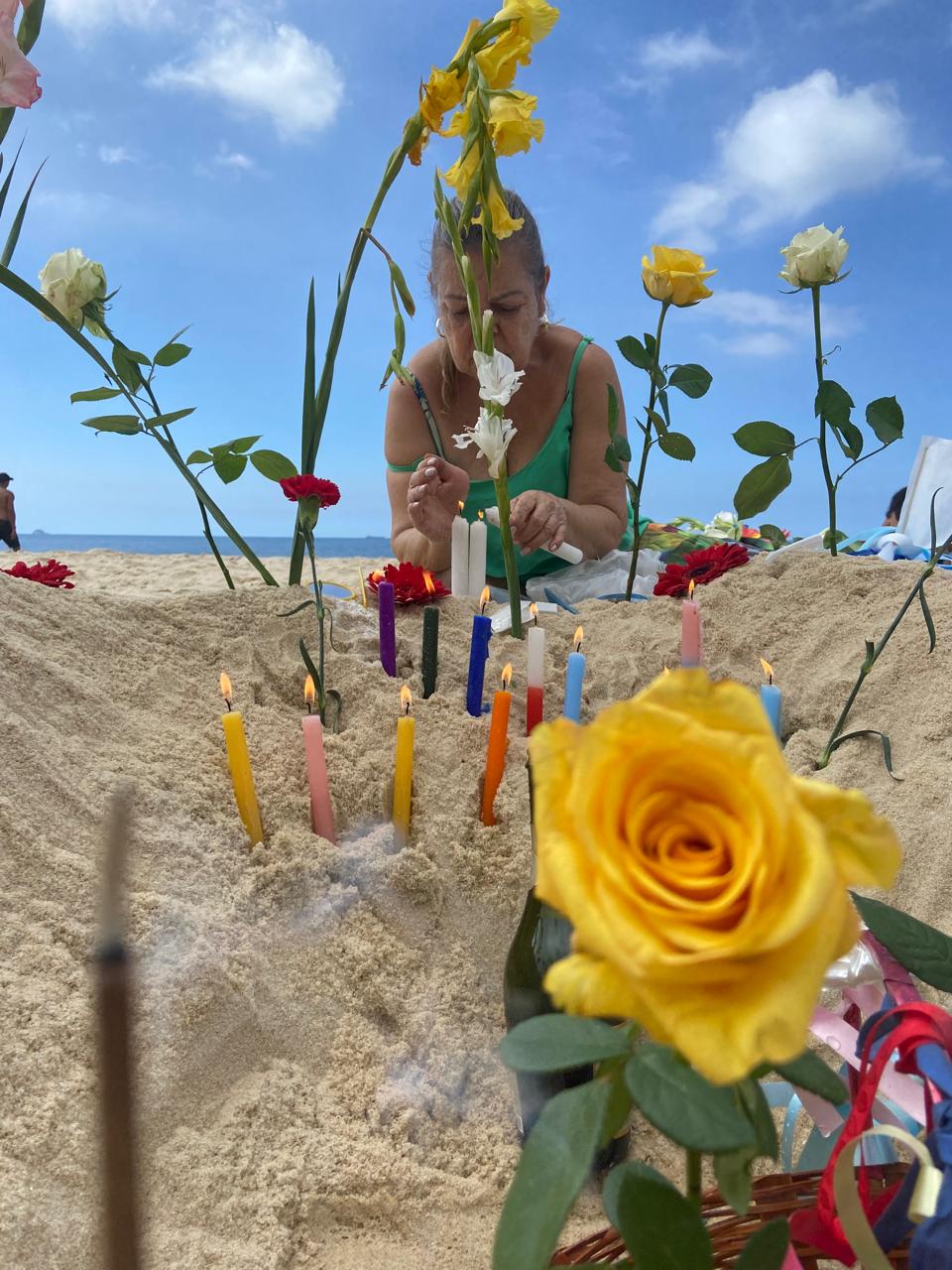 Rosa amarela e velas coloridas em oferenda na praia