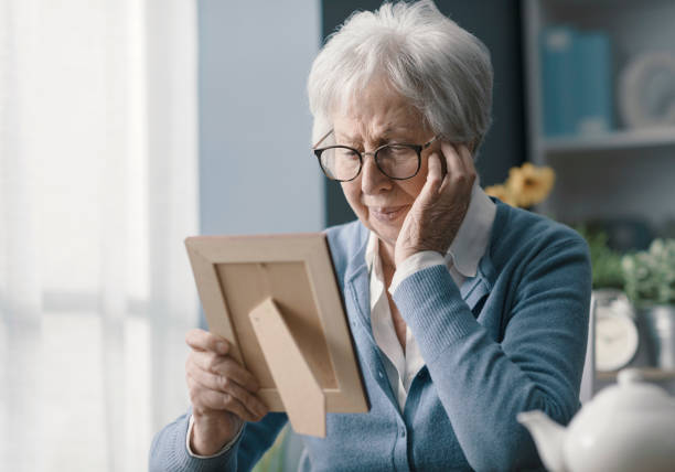 Older woman sitting quietly at a table, looking thoughtful