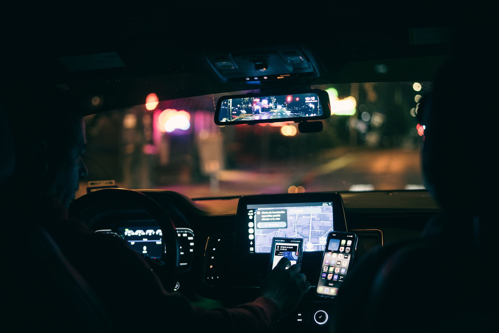 Motorista de aplicativo dirigindo à noite com o app de corridas aberto no celular