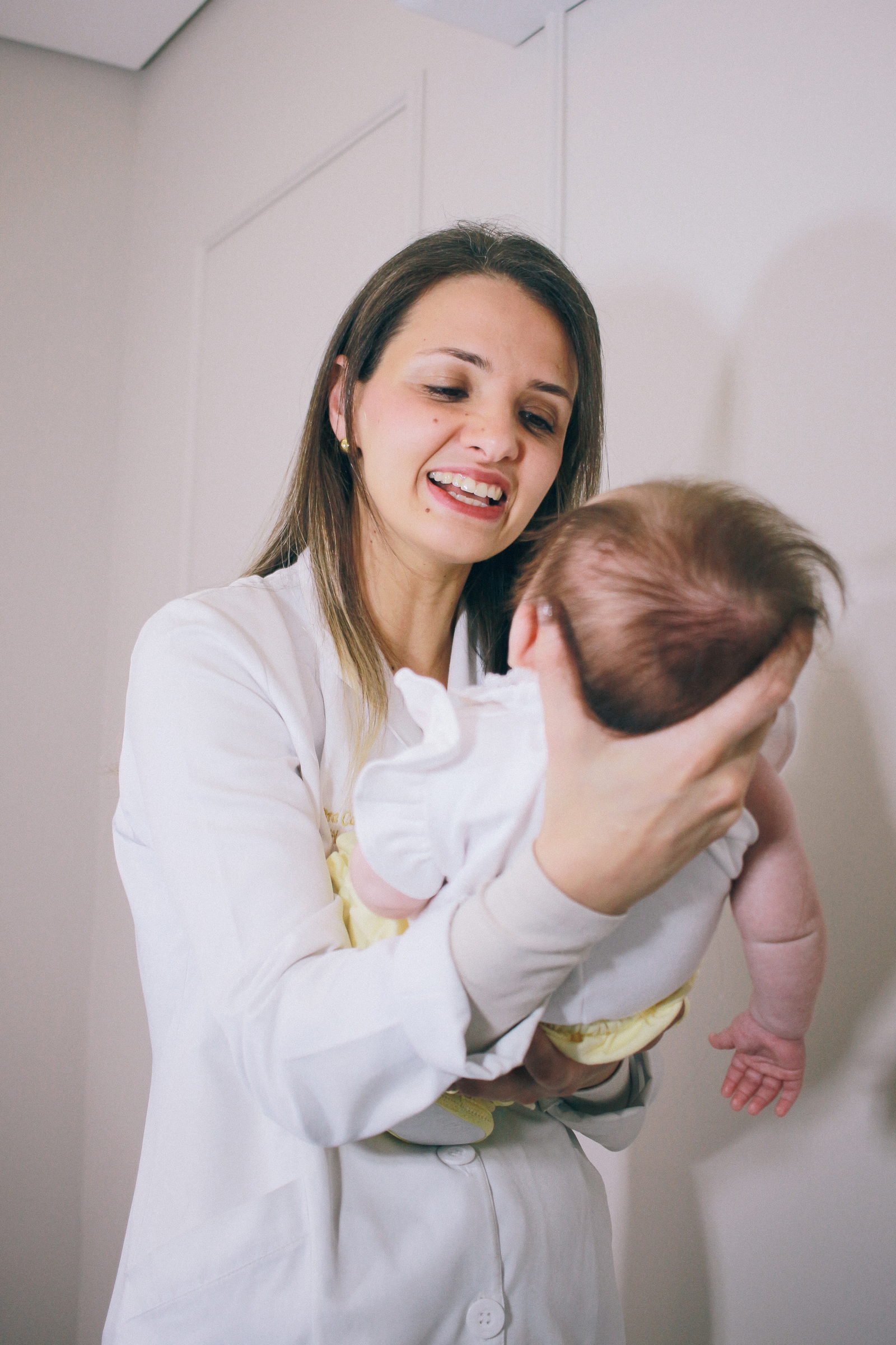 Dra. Carla Tissiane sorrindo com um bebê no colo